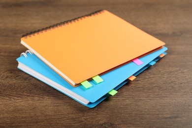 Photo of Notebooks with colorful tabs on wooden table, closeup