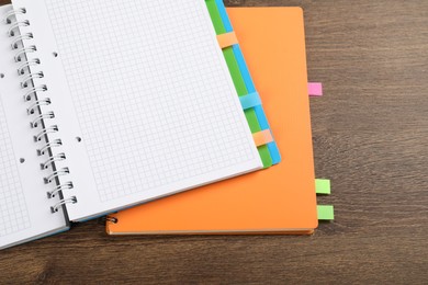 Photo of Notebooks with colorful tabs on wooden table, top view