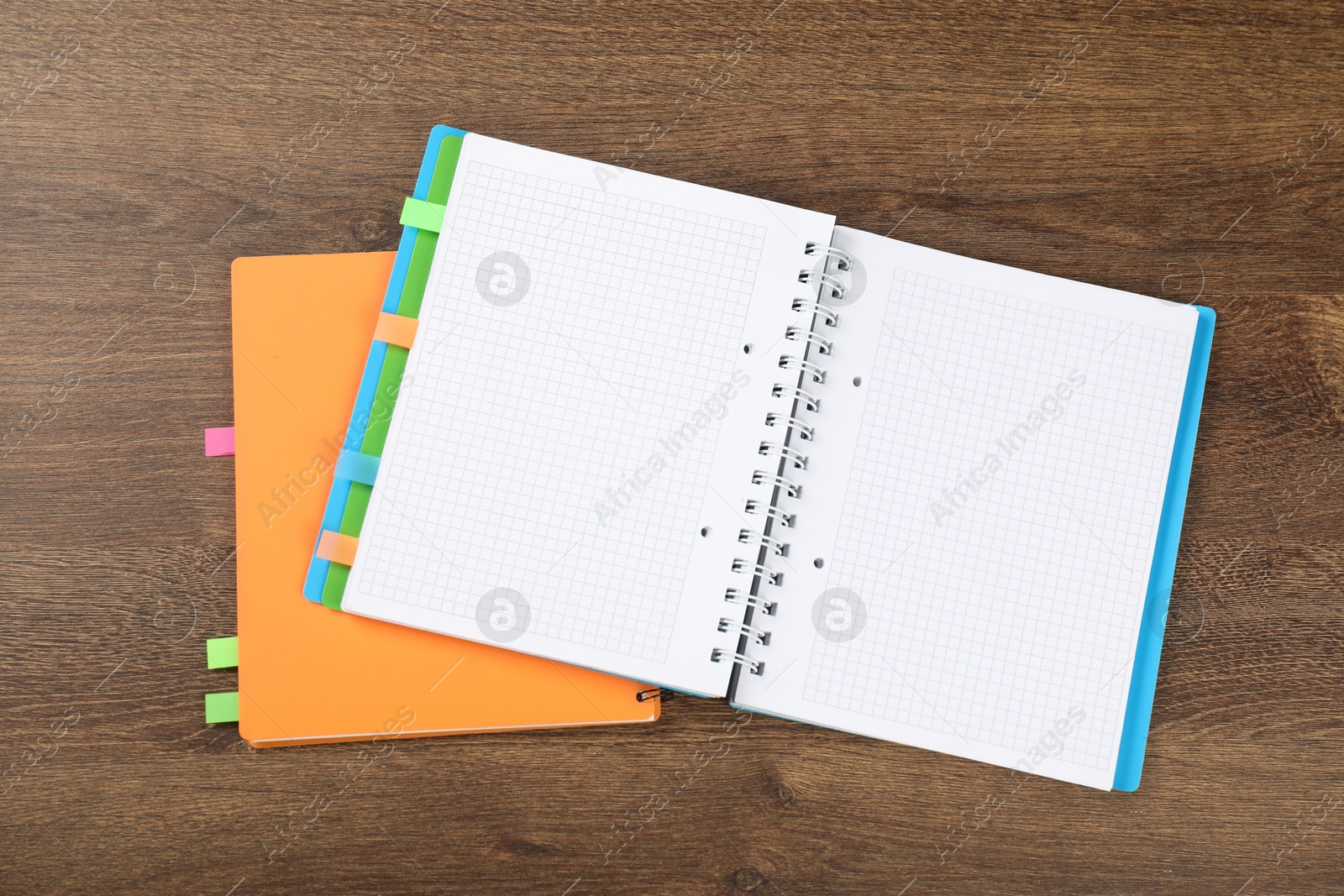 Photo of Notebooks with colorful tabs on wooden table, top view