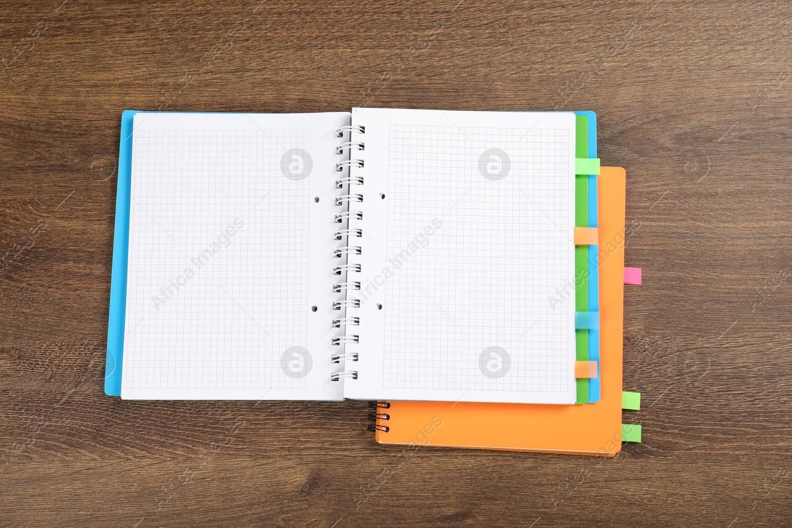 Photo of Notebooks with colorful tabs on wooden table, top view