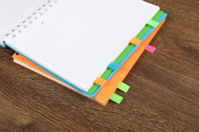 Photo of Notebooks with colorful tabs on wooden table, closeup