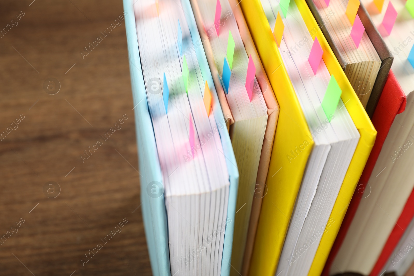 Photo of Books with colorful tabs on brown table, closeup