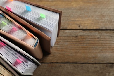 Photo of Books with colorful tabs on wooden table, above view. Space for text