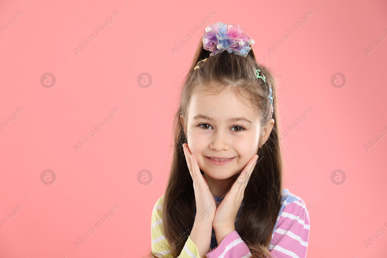 Photo of Happy little girl wearing beautiful hair accessories on pink background, space for text