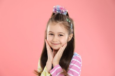 Photo of Happy little girl wearing beautiful hair accessories on pink background