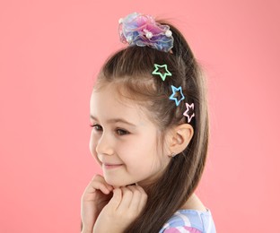 Photo of Happy little girl wearing beautiful hair accessories on pink background