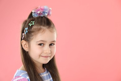 Photo of Happy little girl wearing beautiful hair accessories on pink background, space for text