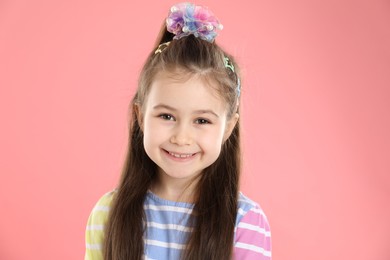 Photo of Happy little girl wearing beautiful hair accessories on pink background