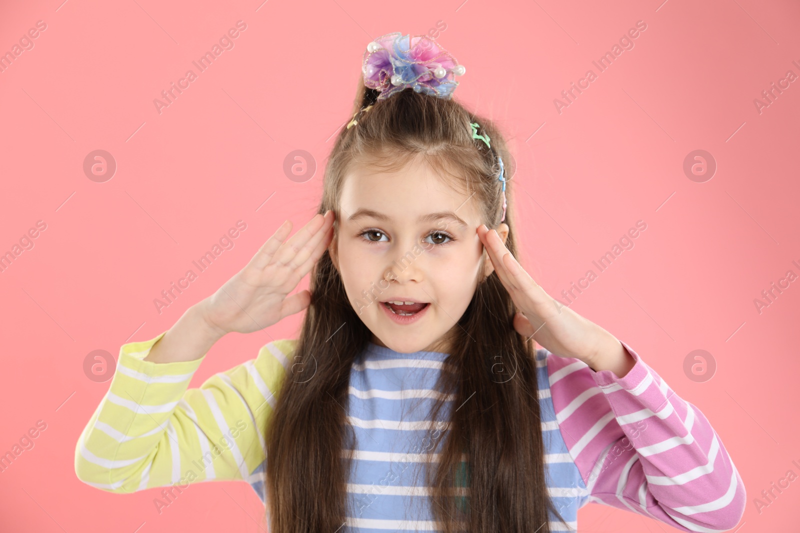 Photo of Little girl wearing beautiful hair accessories on pink background