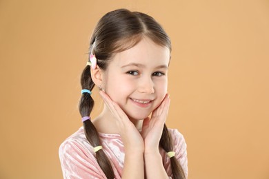 Photo of Little girl wearing beautiful hair accessories on beige background