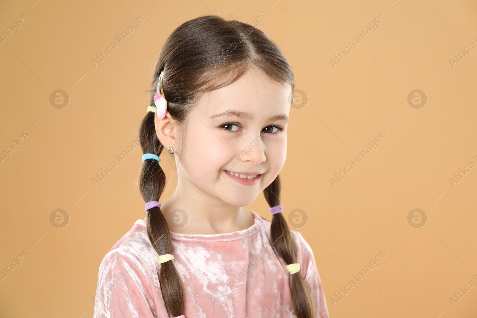 Photo of Little girl wearing beautiful hair accessories on beige background