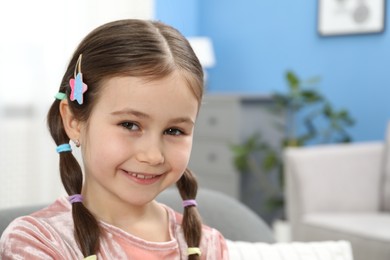 Photo of Happy little girl wearing beautiful hair accessories at home, space for text