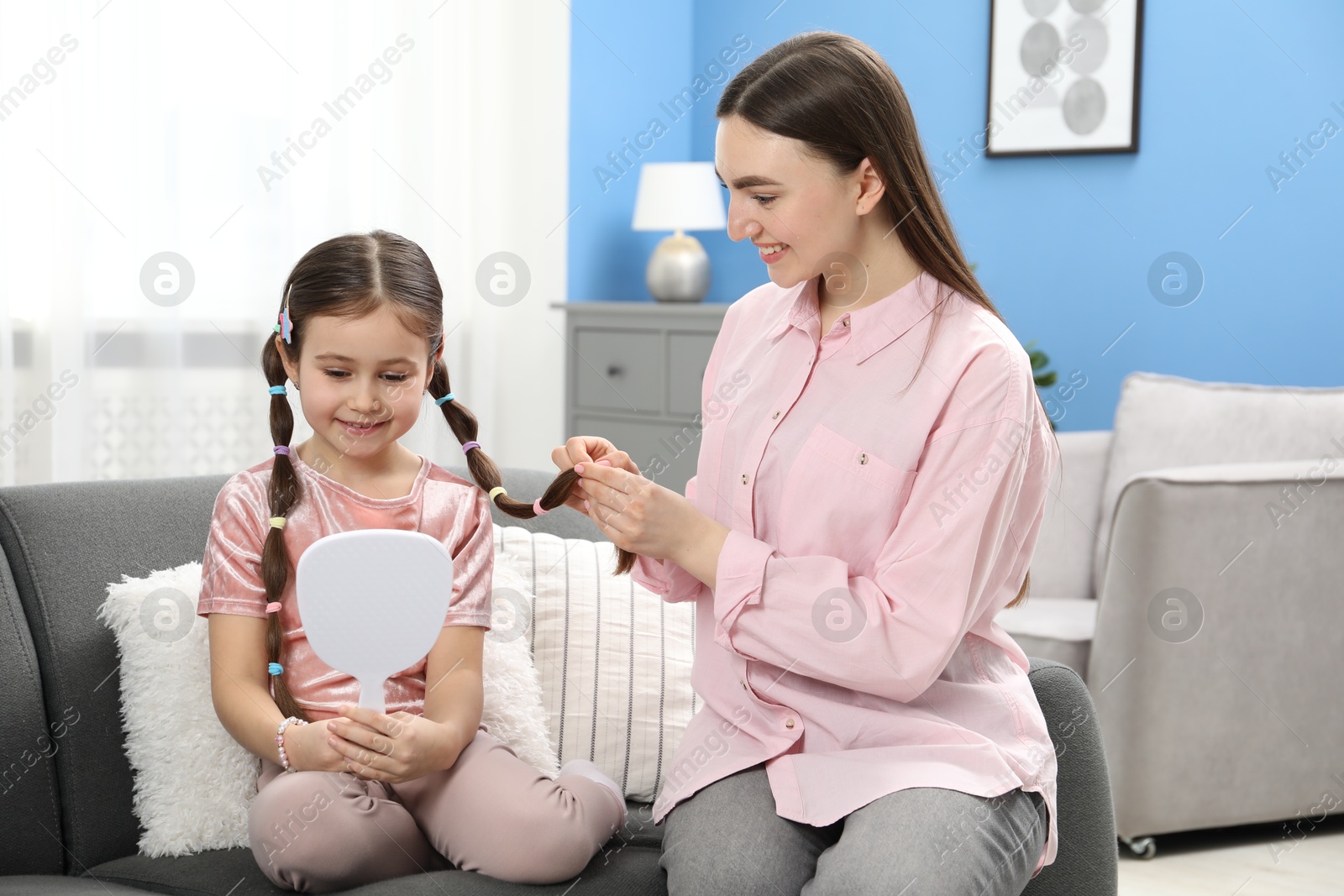 Photo of Mom putting cute accessories onto her daughter's hair at home