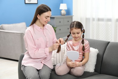 Photo of Mom putting cute accessories onto her daughter's hair at home