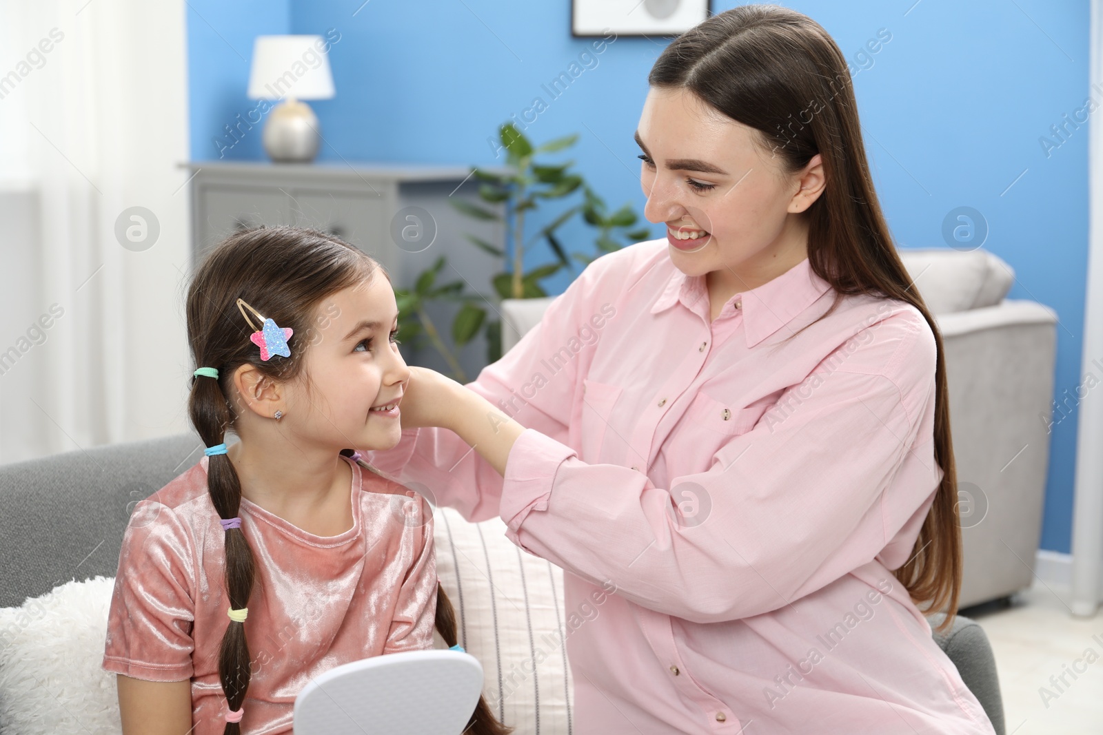 Photo of Mom putting cute accessories onto her daughter's hair at home