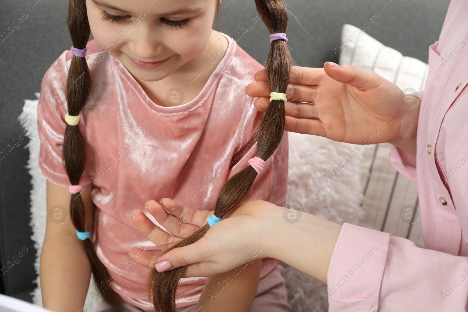 Photo of Mom putting cute accessories onto her daughter's hair at home, closeup