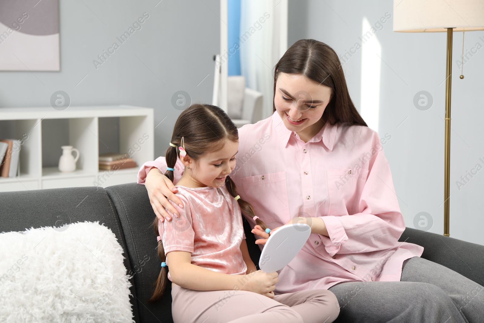 Photo of Mom putting cute accessories onto her daughter's hair at home