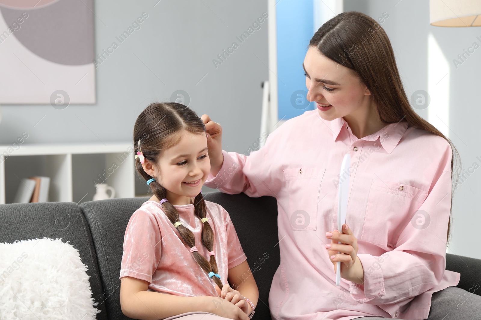 Photo of Mom putting cute accessories onto her daughter's hair at home