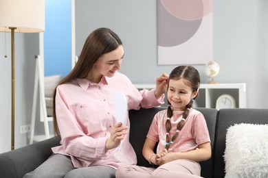 Mom putting cute accessories onto her daughter's hair at home