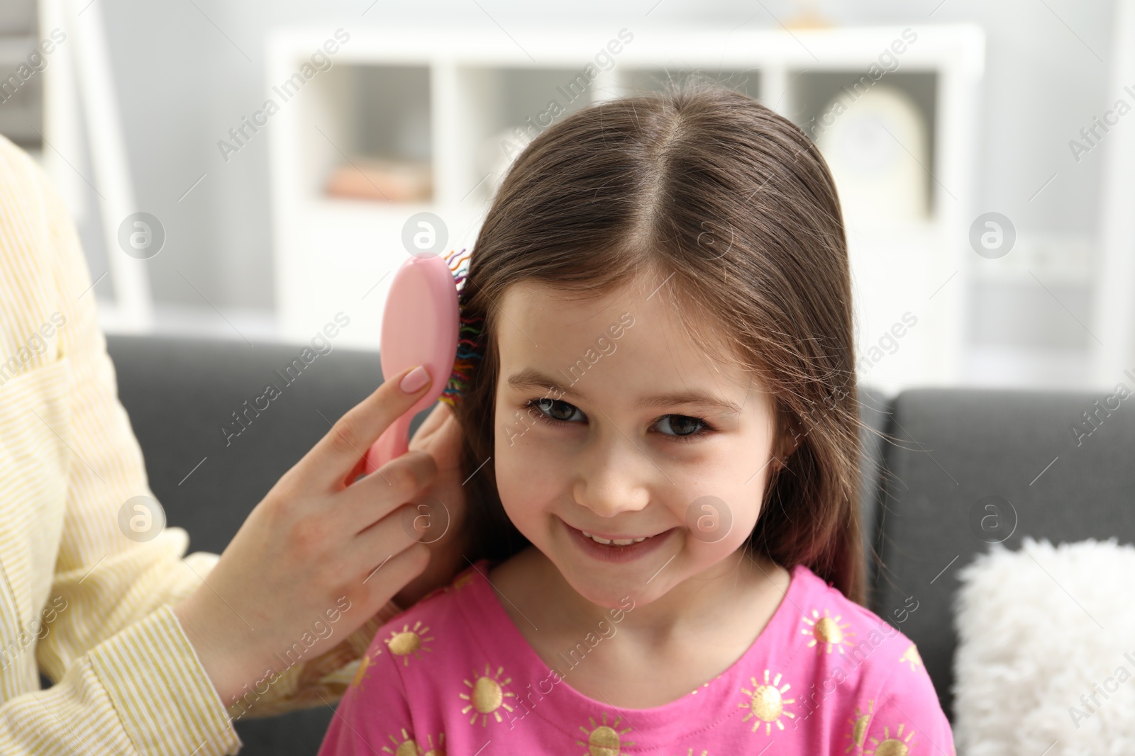 Photo of Mother brushing her little daughter's hair at home, closeup