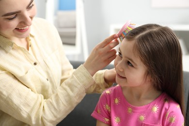 Photo of Mother brushing her little daughter's hair at home