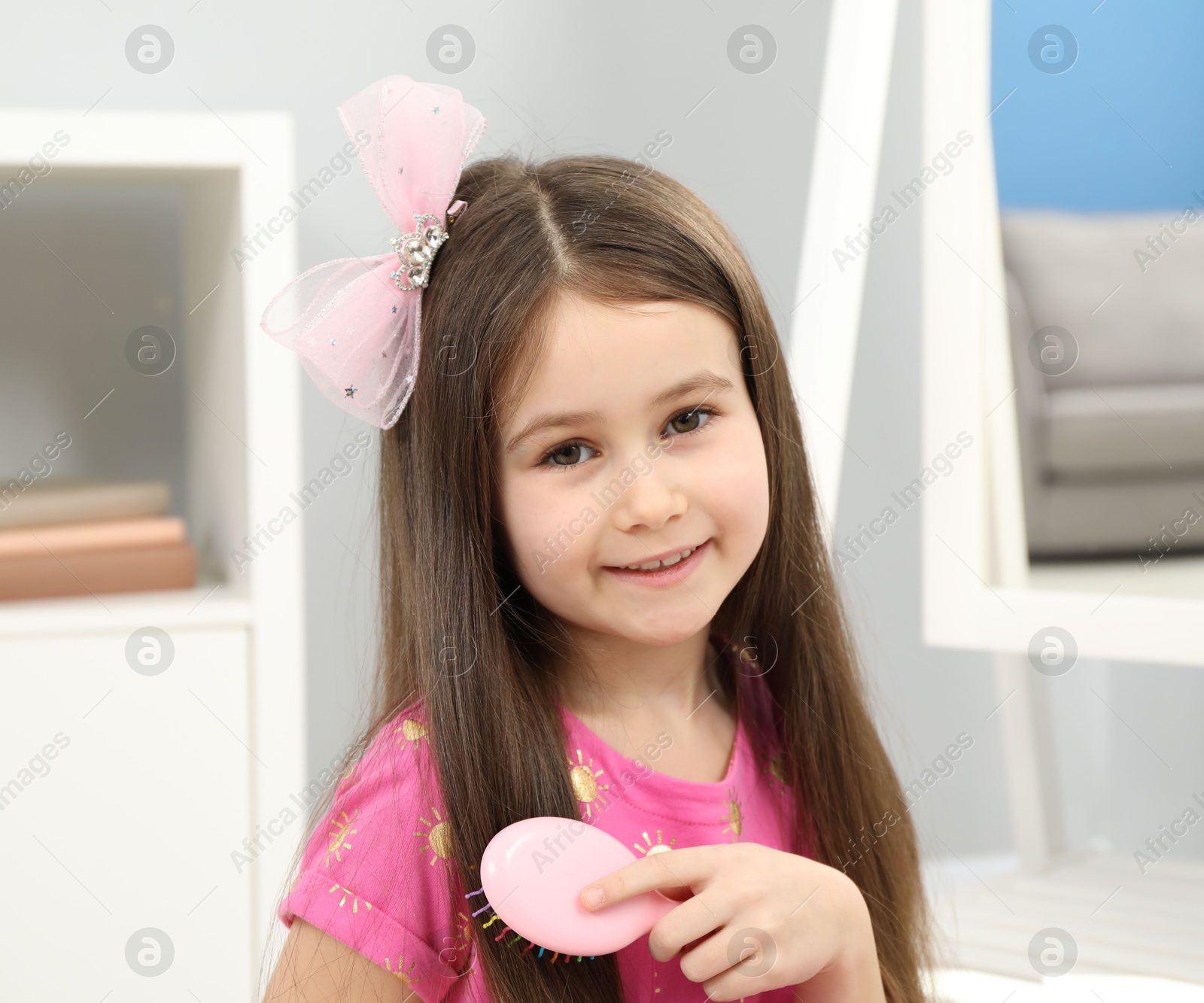 Photo of Little girl brushing her hair at home