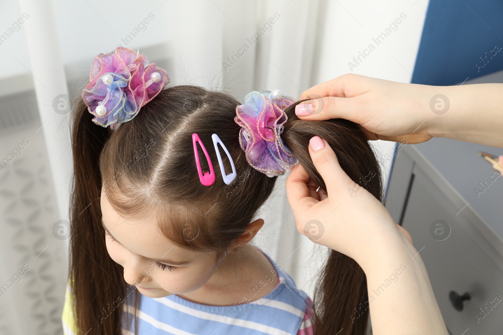 Photo of Mom putting cute accessories onto her daughter's hair at home, above view