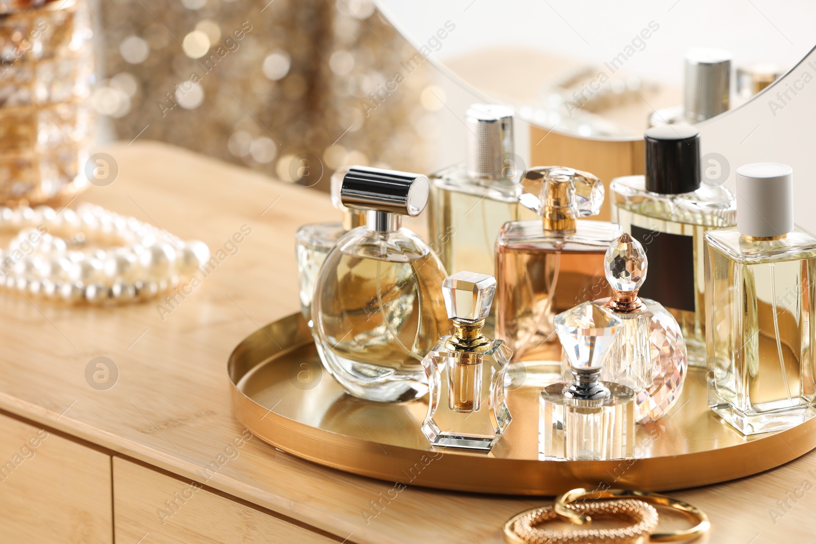 Different luxury perfumes on wooden dressing table indoors Photo of Different luxury perfumes on wooden dressing table indoors