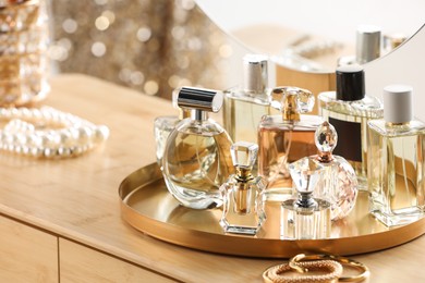 Photo of Different luxury perfumes on wooden dressing table indoors