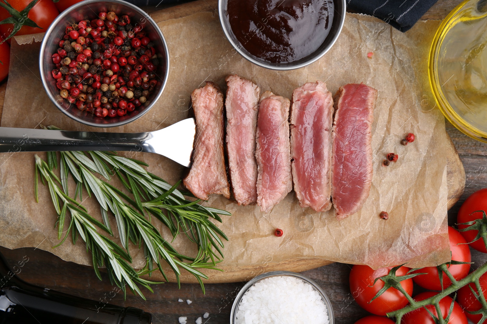 Photo of Delicious sliced beef tenderloin with different degrees of doneness, sauce, spices and other products on table, flat lay