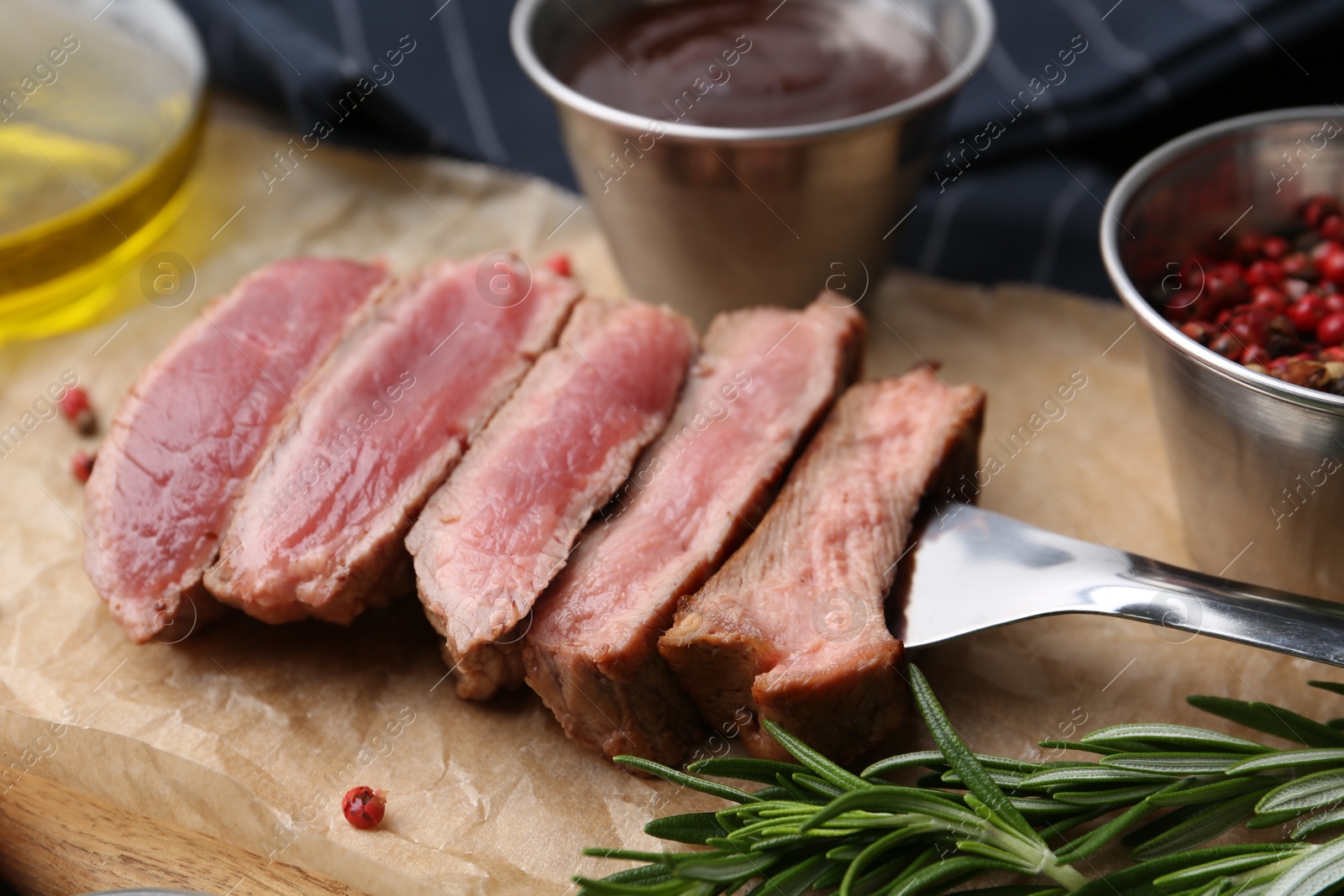 Photo of Delicious sliced beef tenderloin with different degrees of doneness, sauce and spices on table, closeup