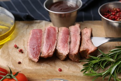 Photo of Delicious sliced beef tenderloin with different degrees of doneness, sauce and spices on table, closeup