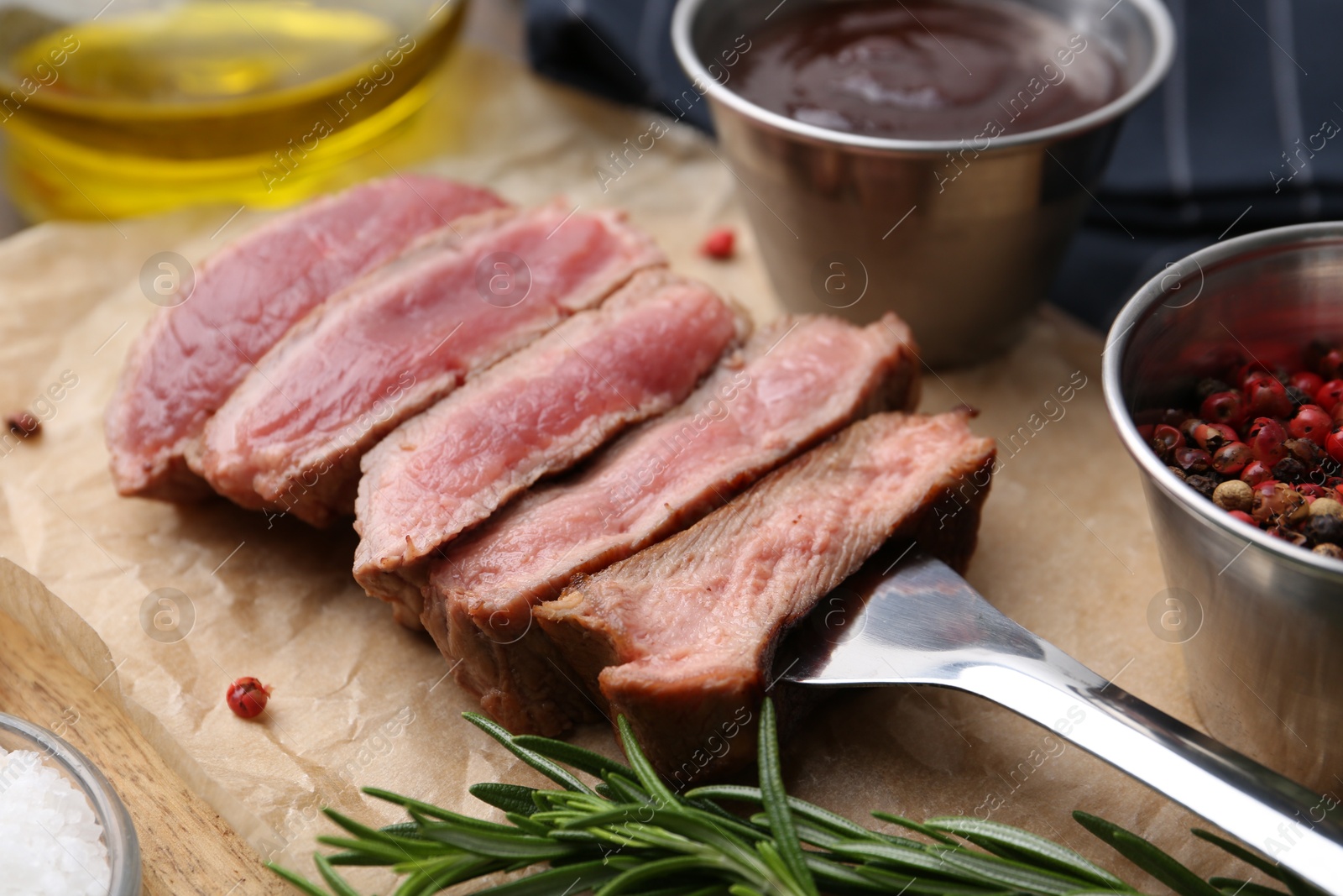 Photo of Delicious sliced beef tenderloin with different degrees of doneness, sauce and spices on table, closeup