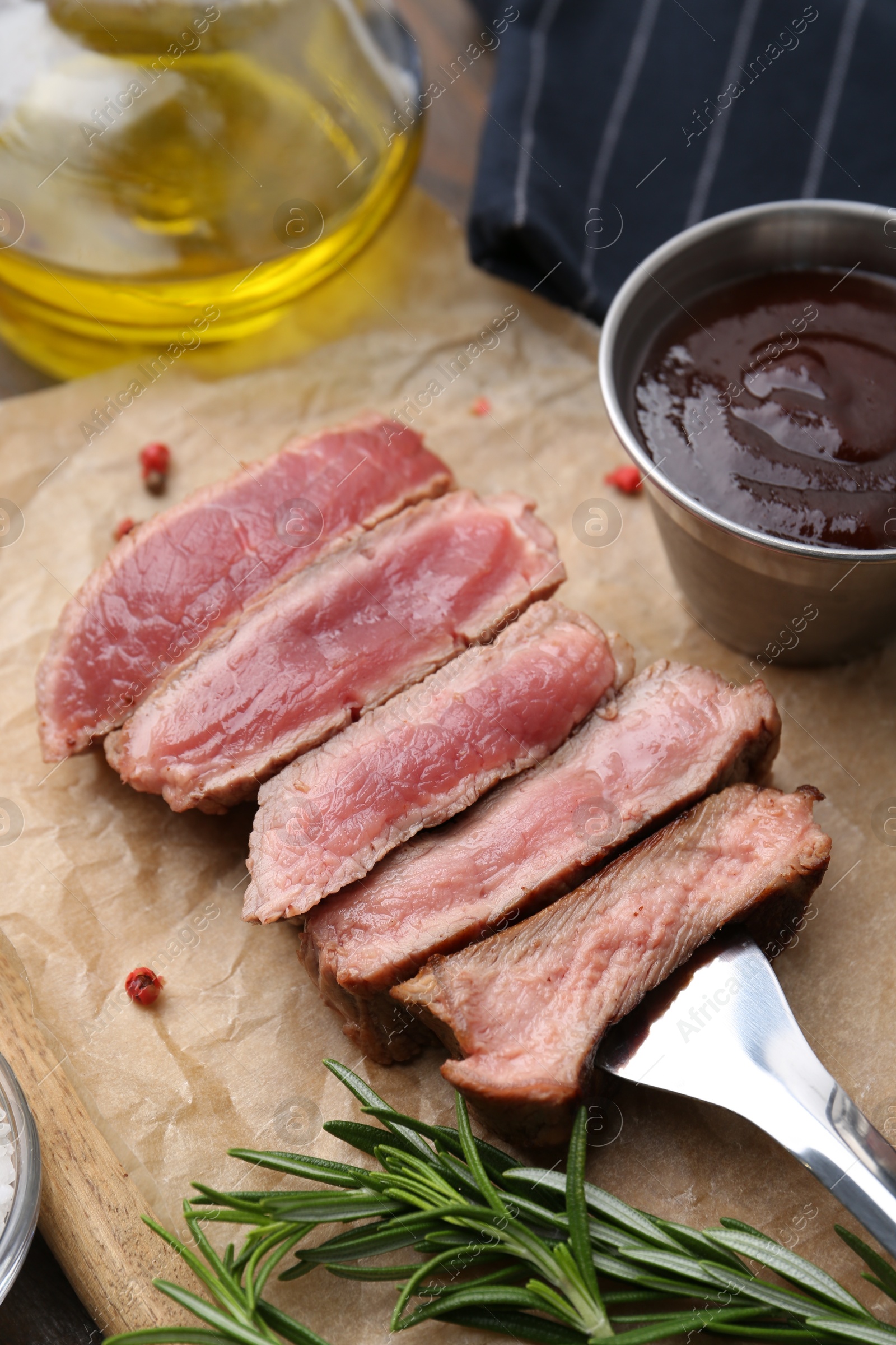 Photo of Delicious sliced beef tenderloin with different degrees of doneness, sauce and spices on table, closeup