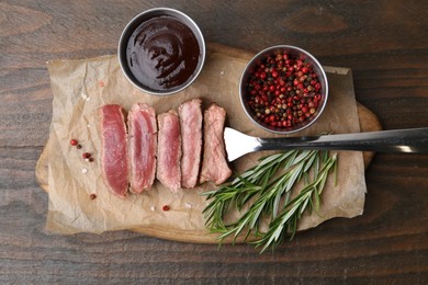 Photo of Delicious sliced beef tenderloin with different degrees of doneness, sauce and spices on wooden table, top view