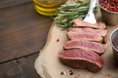 Photo of Delicious sliced beef tenderloin with different degrees of doneness and spices on wooden table, closeup. Space for text