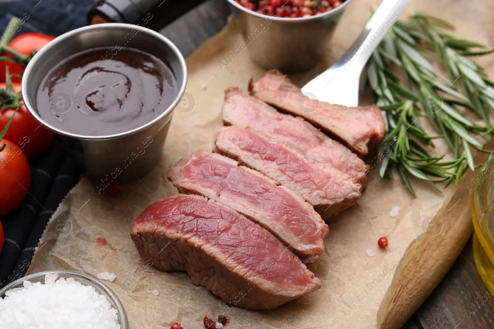 Photo of Delicious sliced beef tenderloin with different degrees of doneness, sauce and spices on table, closeup