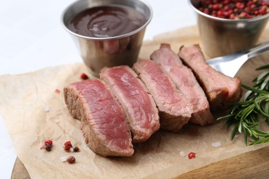 Photo of Delicious sliced beef tenderloin with different degrees of doneness, sauce and spices on light table, closeup