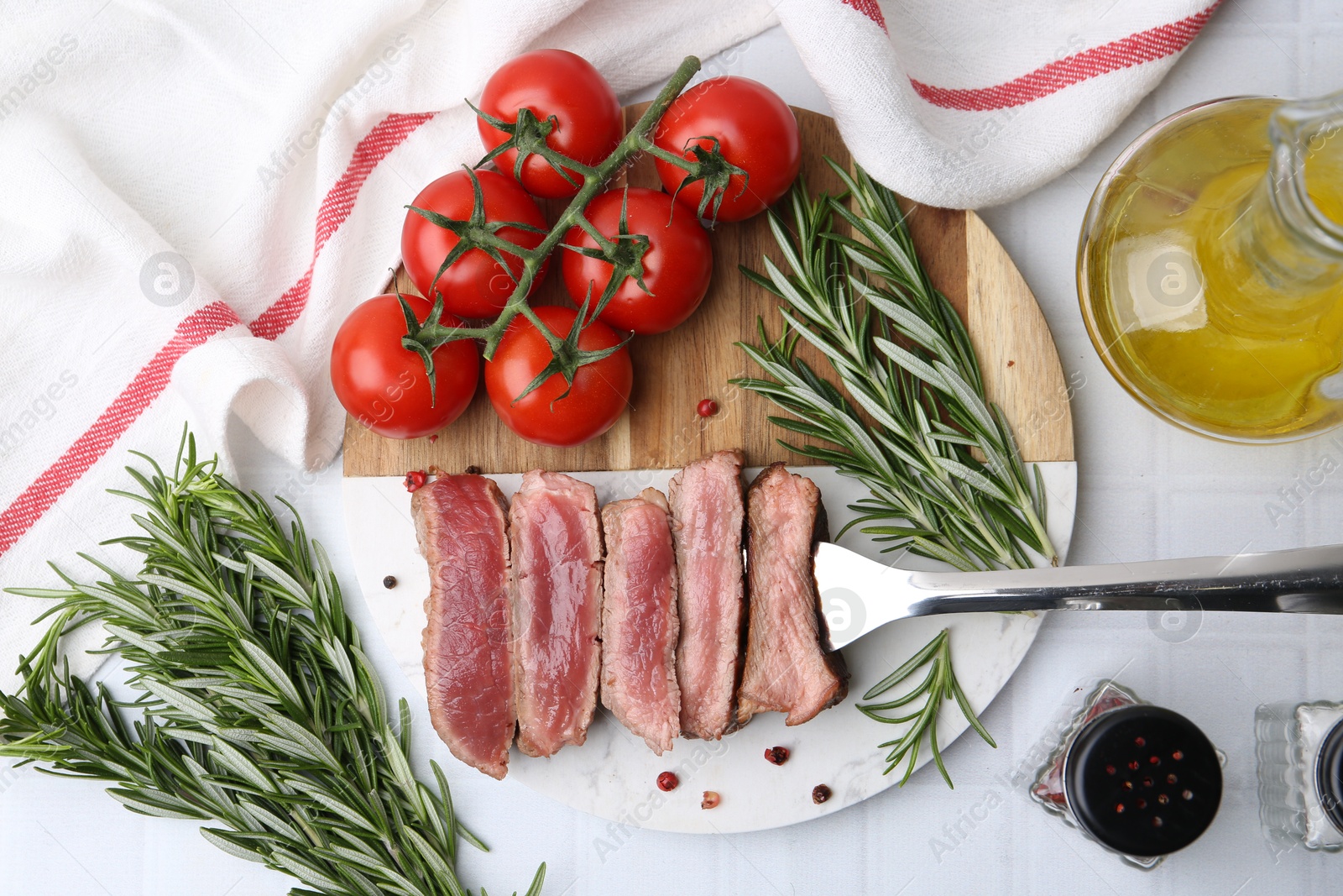 Photo of Delicious sliced beef tenderloin with different degrees of doneness, tomatoes, spices and oil on light table, flat lay