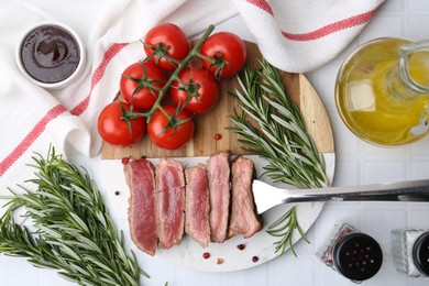 Photo of Delicious sliced beef tenderloin with different degrees of doneness, tomatoes, sauce, spices and oil on light table, flat lay