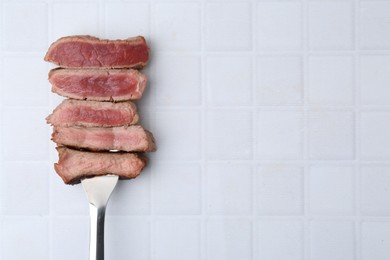 Photo of Delicious sliced beef tenderloin with different degrees of doneness on light tiled table, top view. Space for text