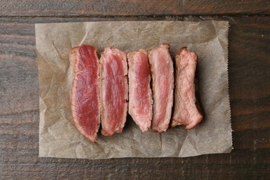 Photo of Delicious sliced beef tenderloin with different degrees of doneness on wooden table, top view