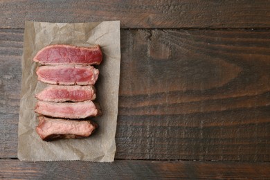 Photo of Delicious sliced beef tenderloin with different degrees of doneness on wooden table, top view. Space for text