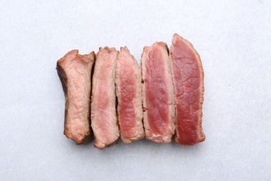 Photo of Delicious sliced beef tenderloin with different degrees of doneness on light table, top view