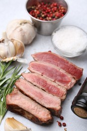 Photo of Delicious sliced beef tenderloin with different degrees of doneness and spices on light table, closeup