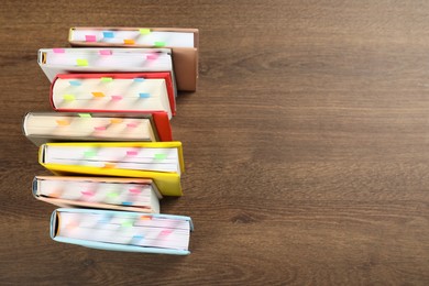 Photo of Books with colorful tabs on wooden table, top view. Space for text