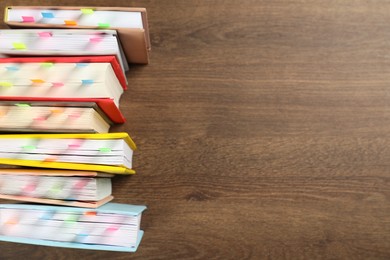 Photo of Books with colorful tabs on wooden table, top view. Space for text