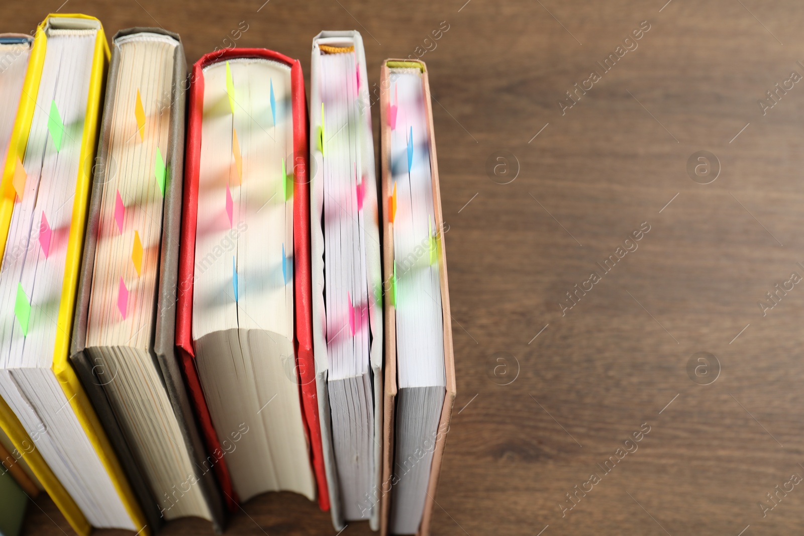 Photo of Books with colorful tabs on wooden table, closeup. Space for text