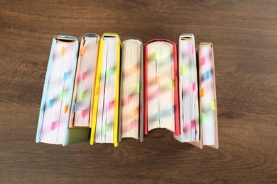 Photo of Books with colorful tabs on wooden table, top view