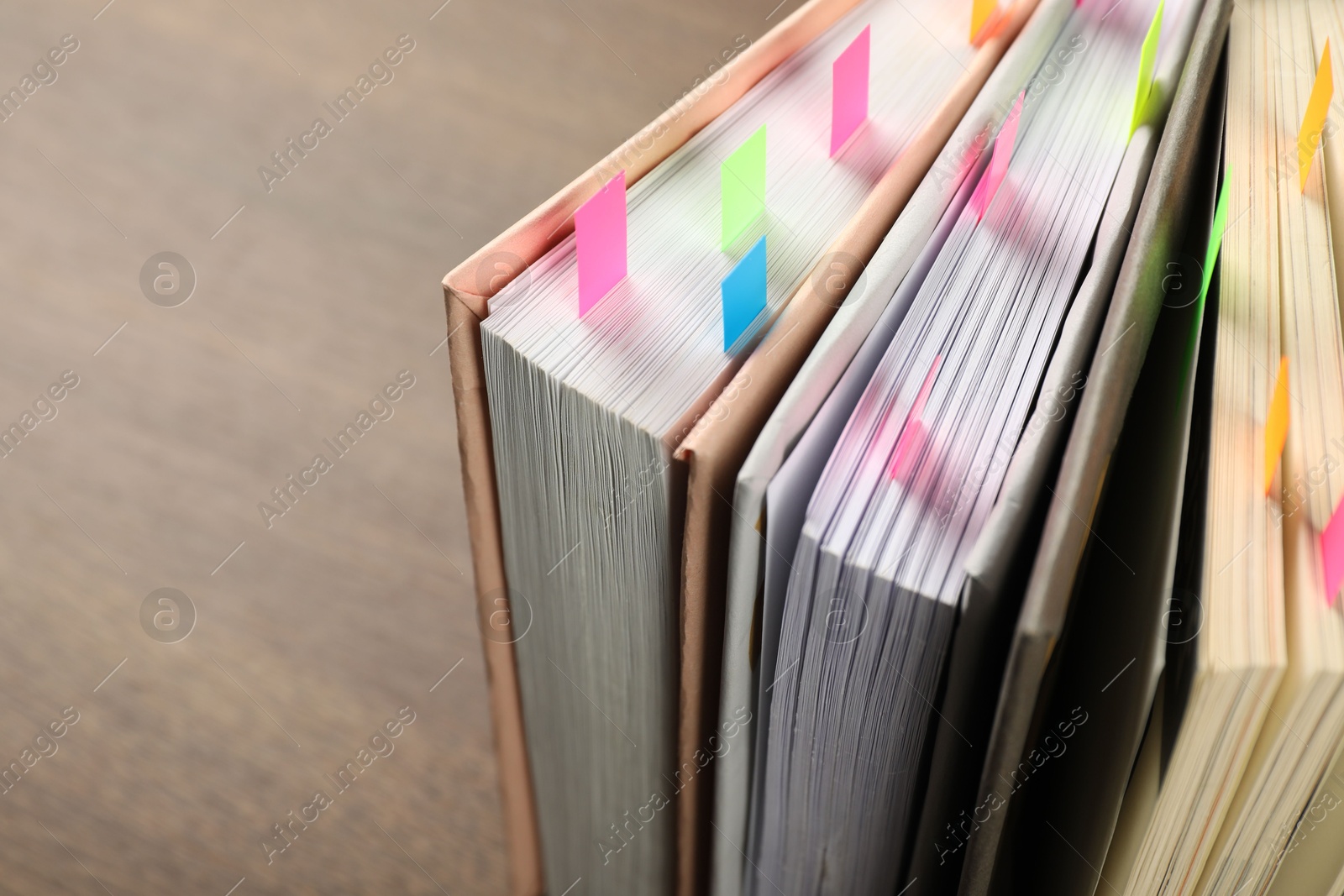 Photo of Books with colorful tabs on brown table, closeup. Space for text